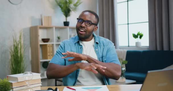Szerethető mosolygós elégedett modern szakállas fiatal afro-amerikai szemüveges beszél a kamerába, és tapsol a kezét a végén az otthoni belső háttér — Stock videók