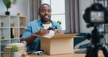 Sevimli gülümseyen mutlu sakallı Afrikalı Amerikalı blogcu evde kameranın önünde oturmuş internet izleyicilerine oyun sahası aldığını anlatıyor.