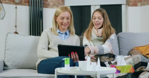 Roztomilý šťastný usměvavý dospívající dívka dávat hlavu na matčiny rameno při revizi spolu legrační a intersting film nebo video na tablet PC, trávení společného volného času doma — Stock video