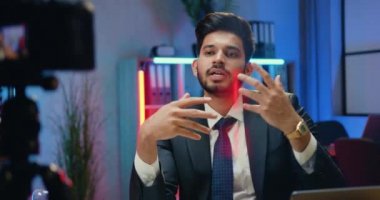 İyi görünümlü, deneyimli, sakallı iş adamı blogcu takım elbiseli internet iş kanalı için video kaydediyor.