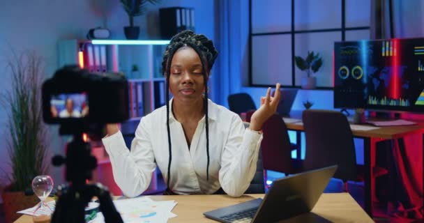 Atraente positivo relaxado moderno Africano americano empresária em elegante desgaste meditando com os olhos fechados e mãos mudra na frente da câmera no escritório da noite sozinho — Vídeo de Stock