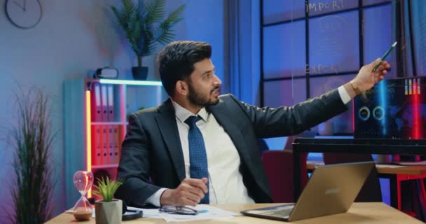 Attractive positive successful experienced bearded businessman sitting in front of camera in evening office and explaining records on glass wall,gesturing alright symbol and clapping hands — Stock Video