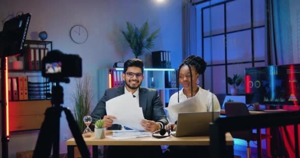 Aantrekkelijke tevreden professionele succesvolle multi-etnische zakenmensen gooien een vel papier over hun hoofd en geven high five elkaar na het einde van video chat in het avondkantoor — Stockvideo