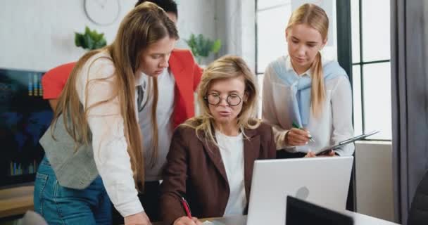 Gerente bem sucedida analisar papelada, assinar contratos durante trabalho de conversa com colegas, juntos se reúnem na mesa de briefing e compartilhar ideias em trabalho em equipe — Vídeo de Stock