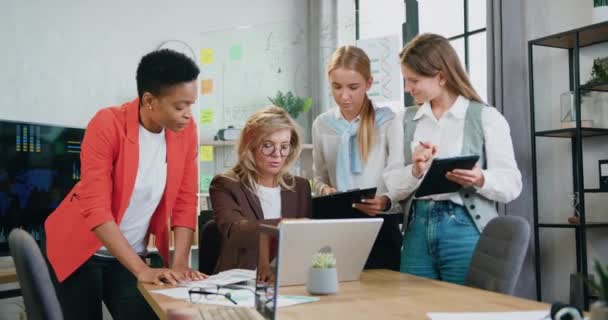 Успішні багаторасові ділові жінки, які працюють з ноутбуком і планшетом разом в офісі — стокове відео
