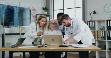 Çekici, neşeli, başarılı, çok ırklı, yetenekli doktorlar modern tıp ofisinde yapılan ortak toplantıda dizüstü bilgisayardan iyi haberler alıyorlar. Tıp alanında başarı ve şans.