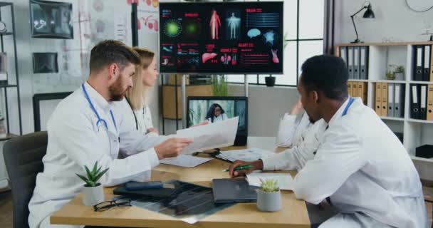Attractive confident experienced purposeful multiethnic doctors reporting in front of female african american main manager of clinic via online chat on computer — Stock Video