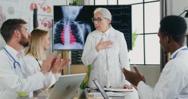Belle femme médecin mature réussie remerciant pour les applaudissements de ses collègues multiethniques motivés qualifiés après son rapport au cabinet médical — Video