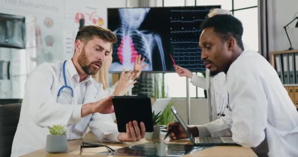 Medical concept where attractive confident skilled multiethnic doctors talking between themselves during joint meeting in clinic office — Stock Video
