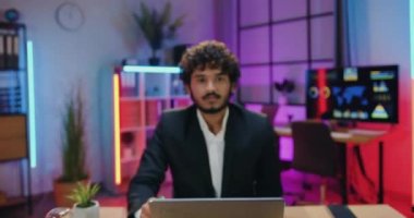 Kamera çekimlerinde gülümseyen, genç, sakallı Asyalı bir iş adamı vardı. Akşam ofisindeki dostça yüz ifadesiyle kameraya bakıyordu.