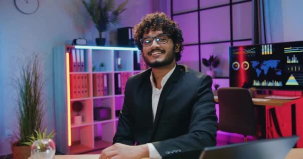 Tampan tersenyum percaya diri profesional berjanggut pengusaha India berkacamata berpose di kamera di kantor malam dengan ok tangan simbol, pandangan depan — Stok Video