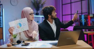 Çekici, olumlu, başarılı Arap, iki erkek ve kadın iş adamının akşam ofisinden meslektaşlarıyla çevrimiçi bir toplantı yaptığı iş konsepti.