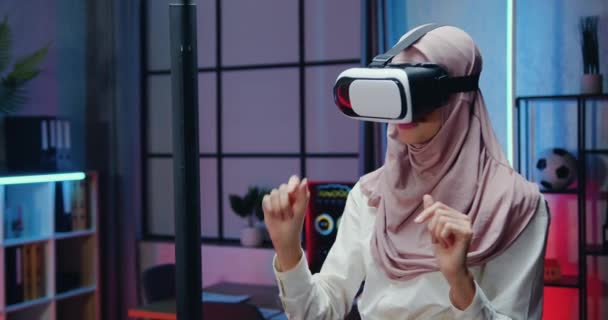 Aantrekkelijk zelfverzekerd slimme ervaren mulsim zakenvrouw in licht violette hijab draagt speciale 3d bril tijdens overwerk in 's nachts verlichte kantoor, business concept — Stockvideo