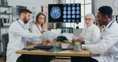 İyi görünümlü, kendine güvenen kadın ve erkek doktorların klinikteki çalışmaları, tıbbi belgeler ve toplantılar sırasında kendi aralarında danışmanlık yapmaktadır.