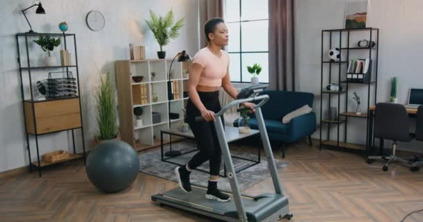 Mooie fit sportieve Afrikaans-Amerikaanse vrouw in sportkleding doen walking oefeningen op loopband tijdens de ochtend thuis workout — Stockvideo