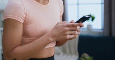 Spor giyim sektöründe faal olmayan zayıf ve formda bir kadın sabah antrenmanı sırasında akıllı telefonunu koşu pistinde kullanır.