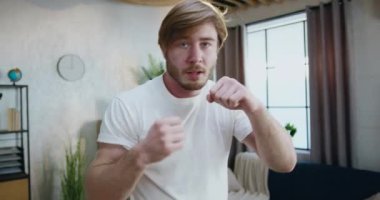 Spor giyim sektöründe aktif, sakallı bir adamın portresi. Evde kameraların önünde boks antrenmanı yapıyor.