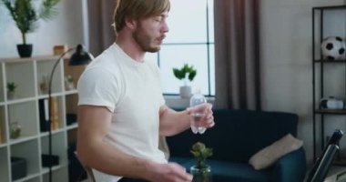 Spor kıyafetleri içinde spor kıyafetleri içinde spor kıyafetli, sabah antrenmanı sırasında plastik şişeden su içen spor düşkünü, sakallı bir adam.