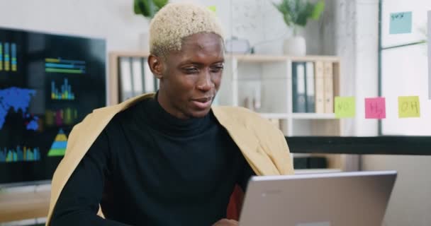 Menutup tempat duduk laki-laki muda di tempat kerja di laptop selama berbicara dengan pelanggan menggunakan web chat, aplikasi konferensi video online — Stok Video