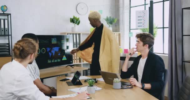 Jonge business mannelijke trainer usin glasplaat en het geven van een corporate presentatie voor drie voor zakenmensen in het moderne kantoor — Stockvideo