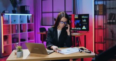 Gözlüklü, sorumluluk sahibi genç bir esmer. Akşam ofisindeki telefon görüşmeleri sırasında kağıt raporlar ve bilgisayar bilgileriyle çalışıyor.