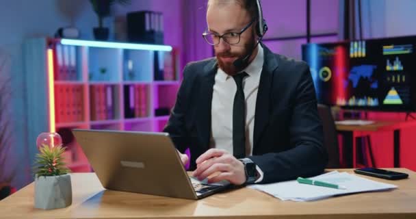 Framgång och lycka koncept där sympatisk förvånad professionell skäggig affärsman i headset få goda nyheter på bärbar skärm och glädjas med att höja händerna — Stockvideo