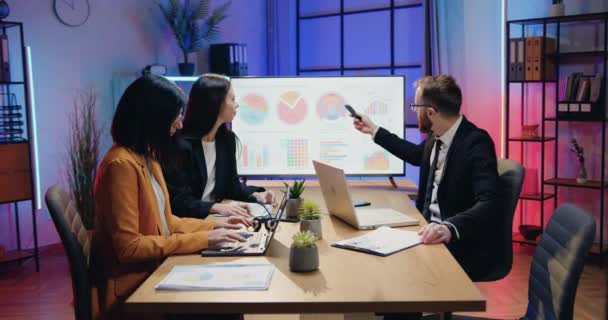 Affärsidé där attraktiva självsäkra skickliga manliga och kvinnliga kontorschefer arbetar tillsammans på kvällskontoret och diskuterar presentation på digital whiteboard — Stockvideo