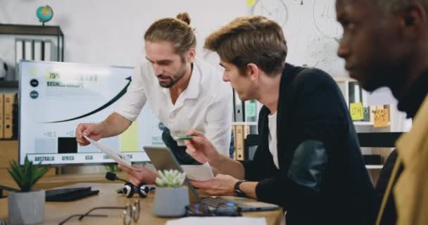 財務書類を扱う多様な男性ビジネスの人々がアイデアをブレーンストーミングし、明るい現代のオフィスで成功戦略にチームワークを計画します。 — ストック動画