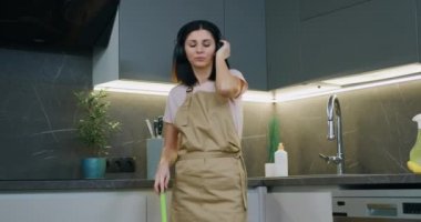 Ev hanımı kulaklıkla müzik dinliyor, yalınayak dans ediyor ve mutfak evinde ıslak paspas ile yerleri yıkıyor..
