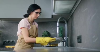 Ev hanımı esmer kadının modern iç mekan mutfağında her gün bulaşık yıkamasının yan görüntüsü.
