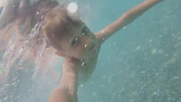 Fotografía submarina de un niño de 7-8 años nadando en el mar Adriático azul con los ojos abiertos con cámara de acción en la mano. Estilo de vida — Vídeo de stock