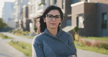 Güzel, kendine güvenen beyaz bir kadının ön portresi. Güzel bir yüzü var. Otomatik kapıda yalnız poz veren kameraya bakıyor.