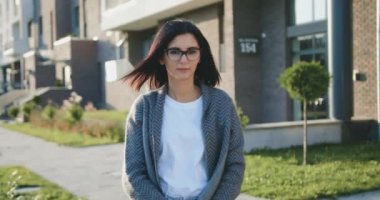 Gün batımında şehir caddesinde yürürken kameraya bakan beyaz bir kadının portresi.