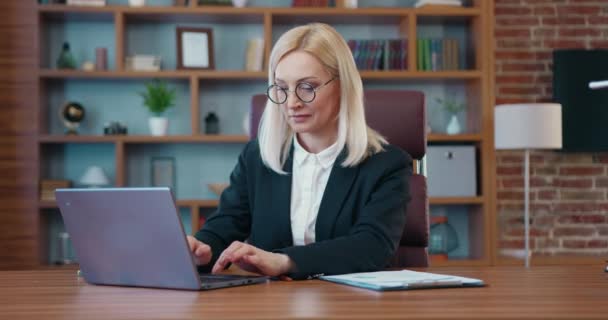 Красивая блондинка в деловой одежде работает за компьютером в офисе — стоковое видео