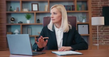 Blond serious doubtful smart senior middle aged old woman looking away thinking of future, looking for inspiration makes a decision feeling lack of ideas