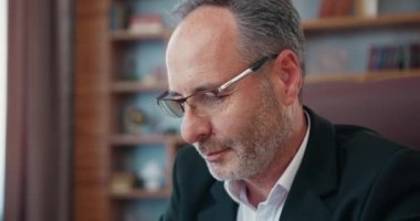 Gözlük takan, dizüstü bilgisayara bakan ve çevrimiçi ticaret piyasası dijital verilerini analiz eden olgun, konsantre iş adamlarına yakın plan.