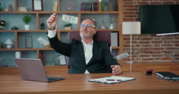 Un om de afaceri fericit cu barbă se bucură de ploaie în timp ce lucrează la birou. Masculul matur se simte distractiv după finalizarea proiectului de lucru care primește dolari. Conceptul de afaceri. — Videoclip de stoc
