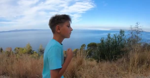 Side view of kid 10 - 11years old athletic boy running on rural road during sunrise at sun dawn over sea beach outdoor. — Vídeo de stock