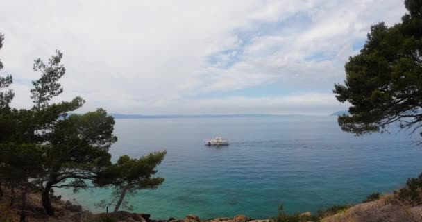 Beautiful nature overlooking the Adriatic sea in which sails white yacht in summer. Makarska riviera, Croatia
