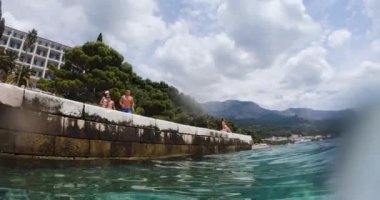 Kafkasyalı genç adam yaz tatilinde dinleniyor, atlıyor ve güneşli bir günde açık Adriyatik Denizi 'ne rıhtımla dalıyor..