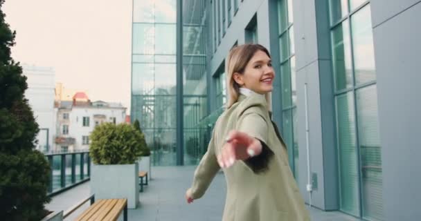 Uśmiechnięta, odnosząca sukcesy młoda kobieta raduje się z sukcesu spacerując ulicą miasta, odwracając się w piękny dzień. Styl życia — Wideo stockowe