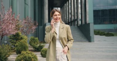 Gün batımında sokakta cep telefonuyla konuşan güzel beyaz bir kadın. İnsanlar ve teknoloji kavramı