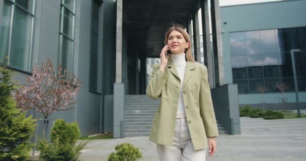 Portré boldog fiatal kaukázusi gyönyörű nő munka után, séta a városban, és beszél okostelefonon. A szabadban. Városi koncepció — Stock videók