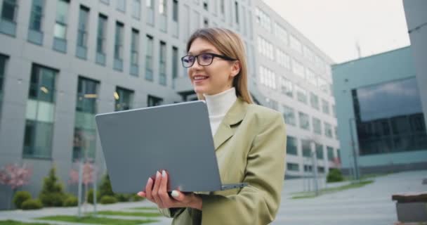 Smiling caucasian businesswoman or student university working or studying online using laptop on street. Remote work or learning concept — Stock Video