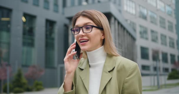 Şehrin finans bölgesinde akıllı telefon kullanan, gözlüklü, başarılı genç sarışın kadını yakından çek. Açık havada.. — Stok video