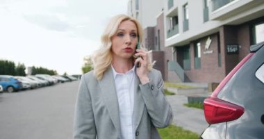 Beyaz, kendine güvenen bir iş kadını şehirde sokakta yürüyor ve iş ortağıyla cep telefonundan konuşuyor ve arabasına biniyor..