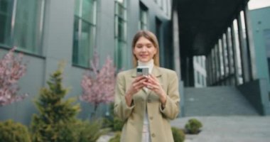 Portre, zaferi sokakta akıllı telefonla kutlayan kızı hayrete düşürdü. İş kadını ofisin arka planındaki cep telefonuna bakarak başarıdan zevk alıyor. Yavaş çekim.