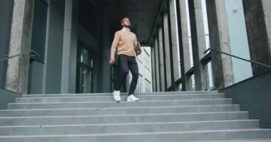 Merdivenlerden inerken aktif olarak dans eden mutlu genç adam. Neşeli adam ofisinin dışındaki merdivenlerde yürür ve komik zafer dansı yapmaya başlar. Yavaş çekim.
