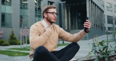 Portre genç işadamı cep telefonu kullanıyor ve modern bir ofis merkezinde konferans sohbeti yapıyor. Yavaş çekim.