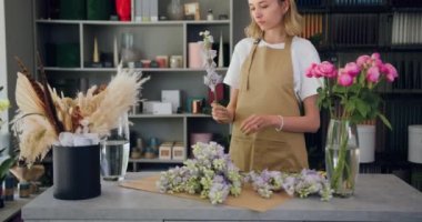 Professional woman florist cuts a flower to create a beautiful bouquet while working in a flower shop. Floral artist working in flower shop studio. Handmade floristry. Slow motion.